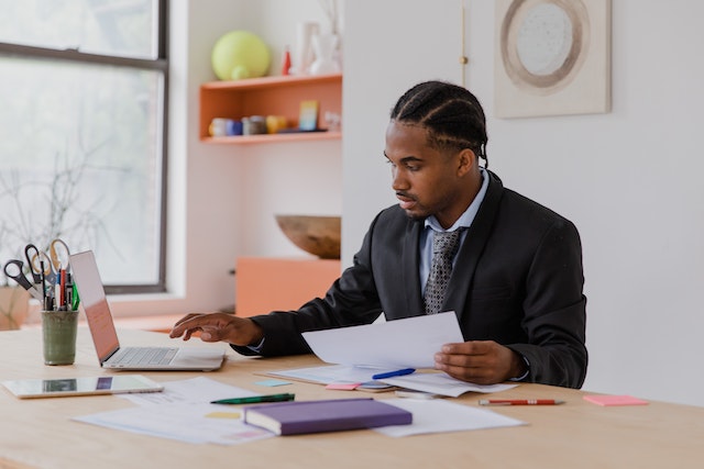 property manager sitting at their desk looking over documents with noting things on their laptop